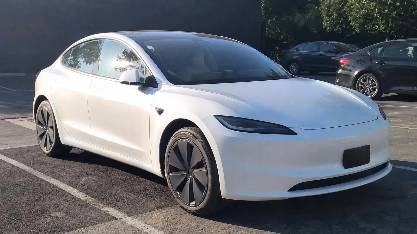 Source photo of a white electric sedan, 1 of 2, taken on a phone