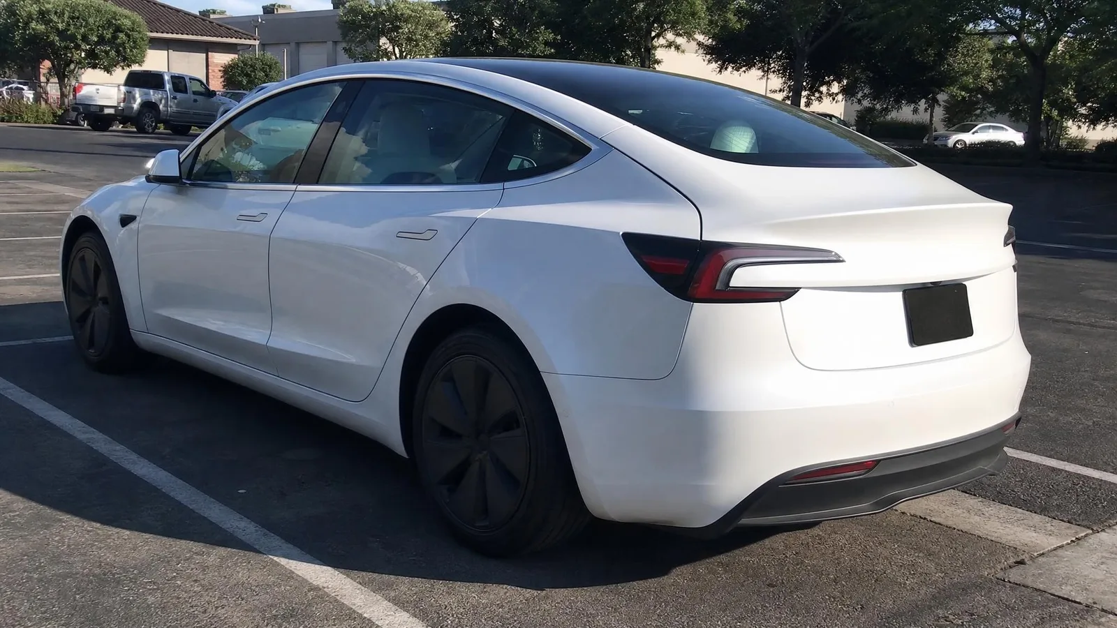 Source photo of a white electric sedan, 2 of 2, taken on a phone