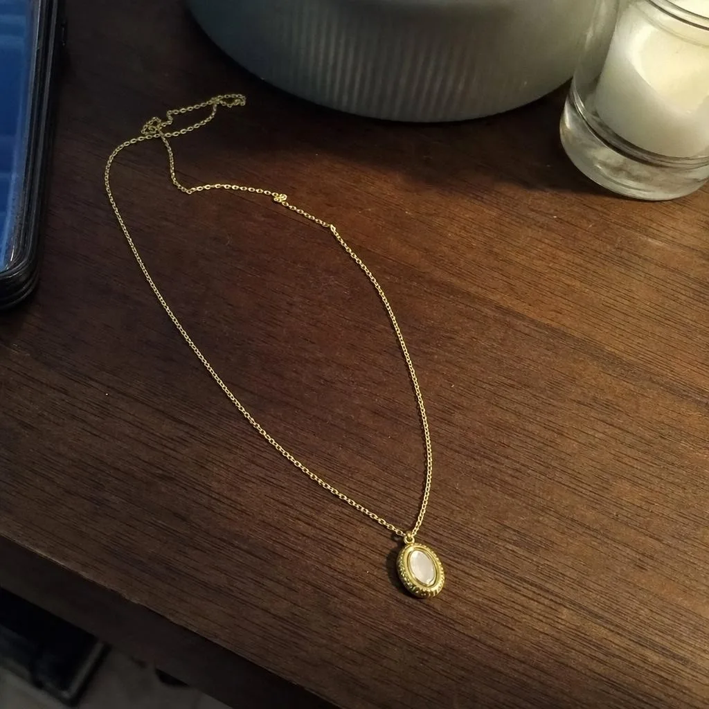 Source photo of a gold pendant necklace, 1 of 2, taken on a phone